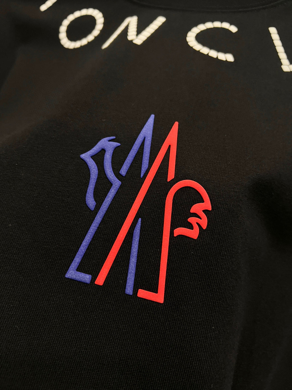 Moncler T-shirt detail, colorful blue and red M logo on black fabric
