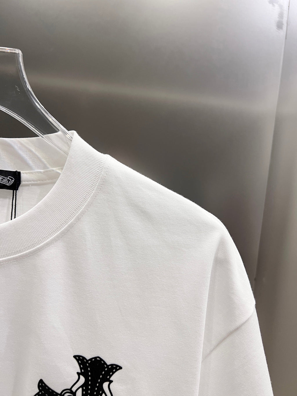 White graphic T-shirt side view with black cross design near the chest