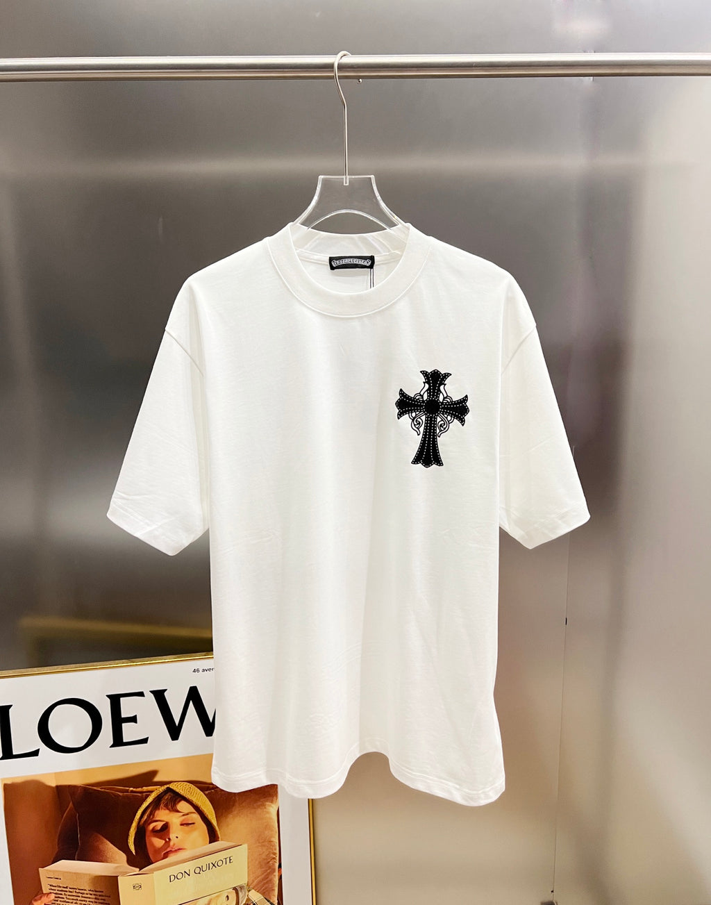 White graphic T-shirt, front view with one black cross appliqué at the chest