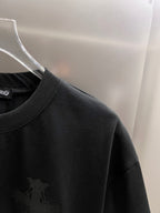 Black T-shirt shoulder and collar with small dark cross emblem