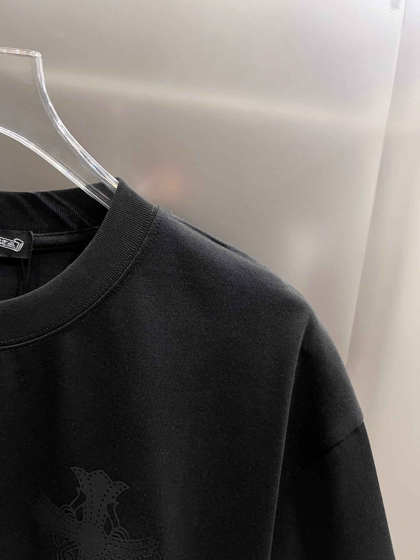 Black T-shirt shoulder and collar with small dark cross emblem
