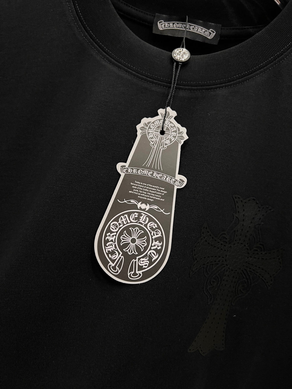 Black T-shirt with hanging price tag and detailed cross emblem