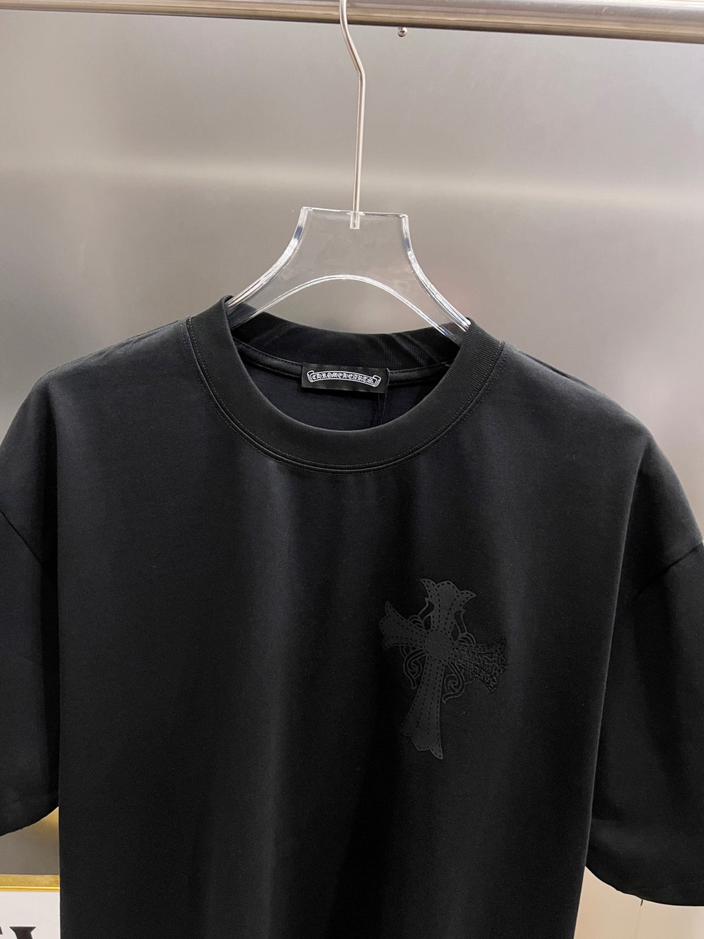 Black short-sleeve T-shirt with small dark cross graphic on front