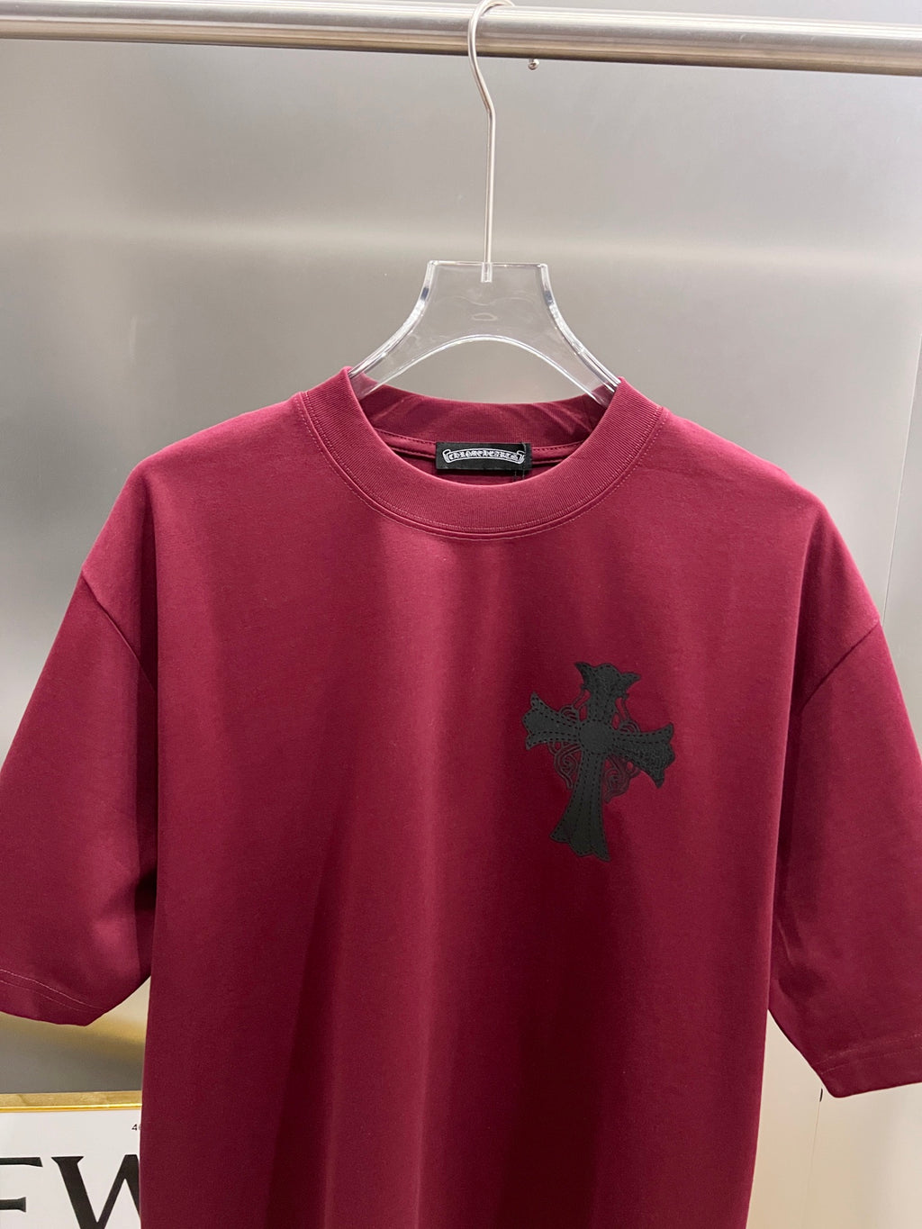 Burgundy short-sleeve T-shirt with small black cross emblem on the front.