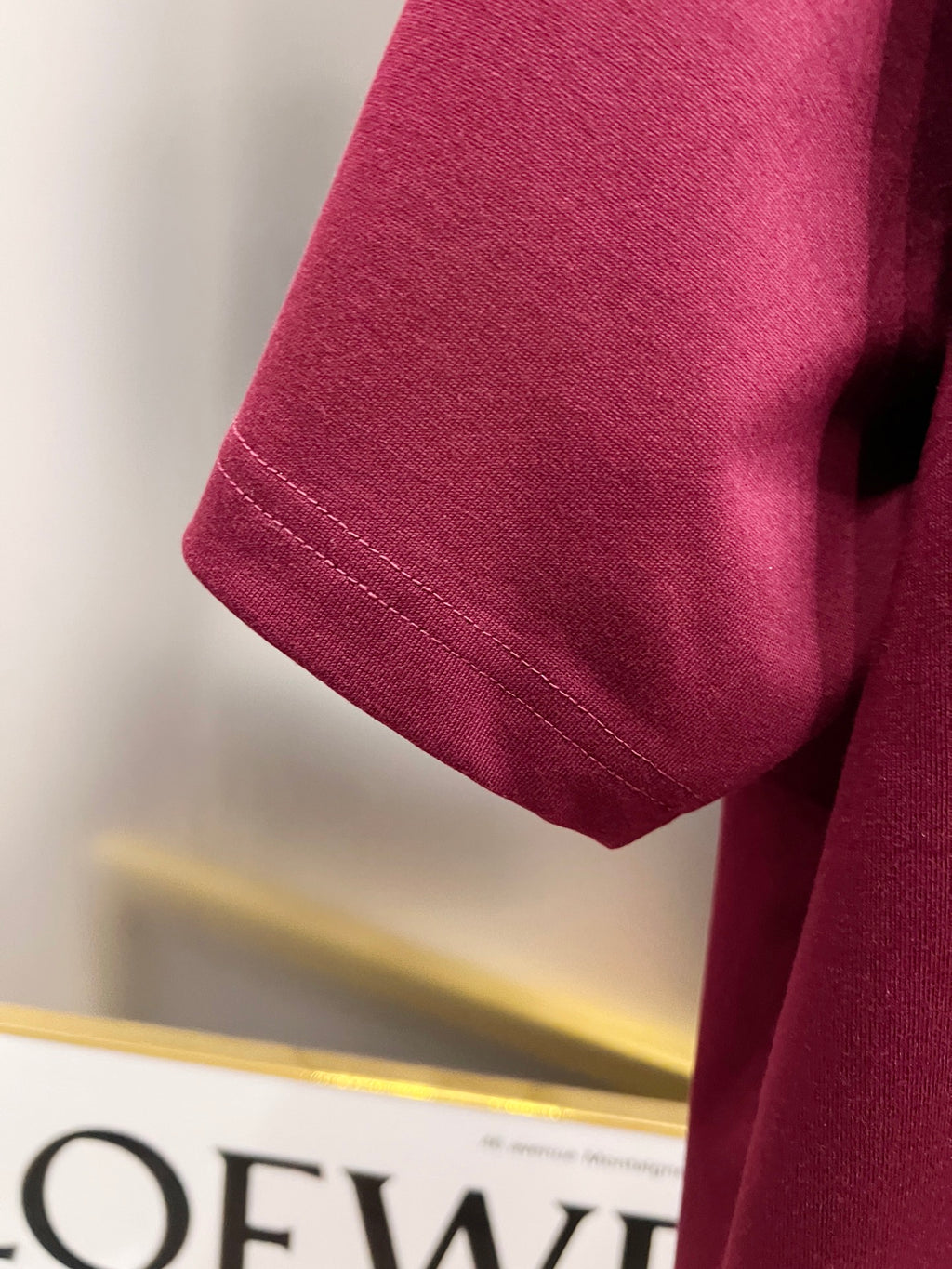 Burgundy short-sleeve T-shirt sleeve with stitched hem detail.