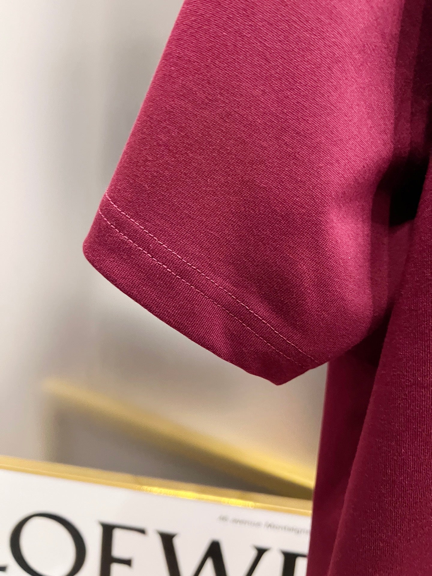 Burgundy short-sleeve T-shirt sleeve with stitched hem detail.
