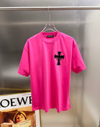 Pink short-sleeve T-shirt with small black cross graphic on the chest