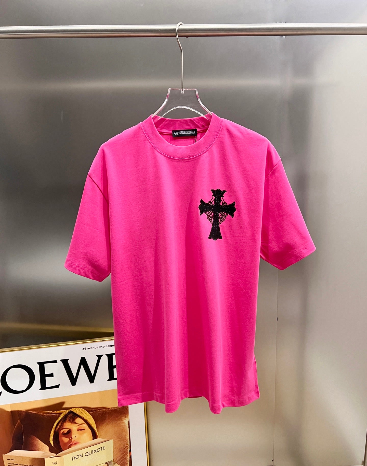 Pink short-sleeve T-shirt with small black cross graphic on the chest