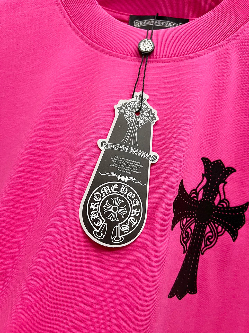 Pink short-sleeve T-shirt with hanging tag charm and black cross applique