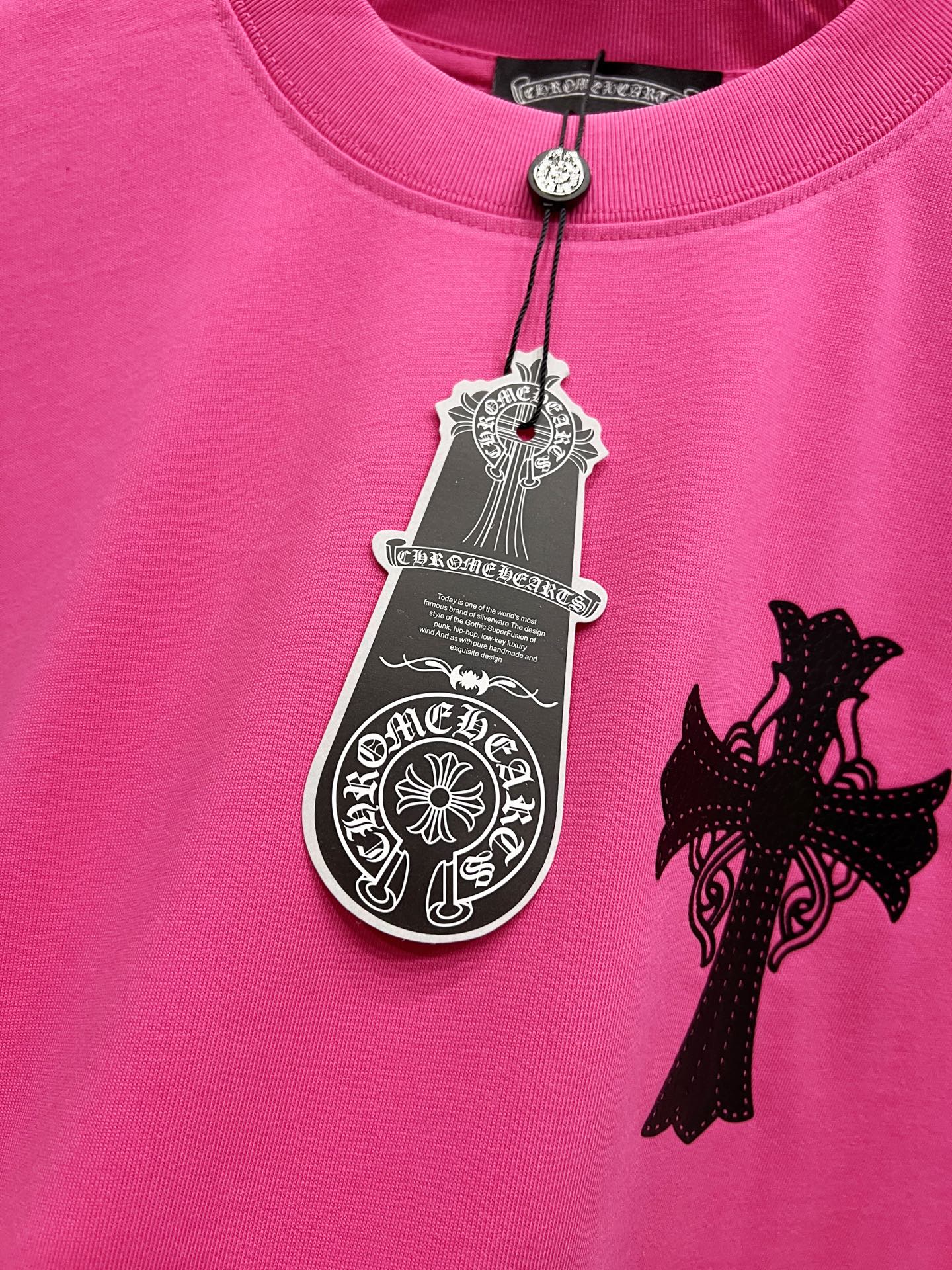 Pink short-sleeve T-shirt with hanging tag charm and black cross applique