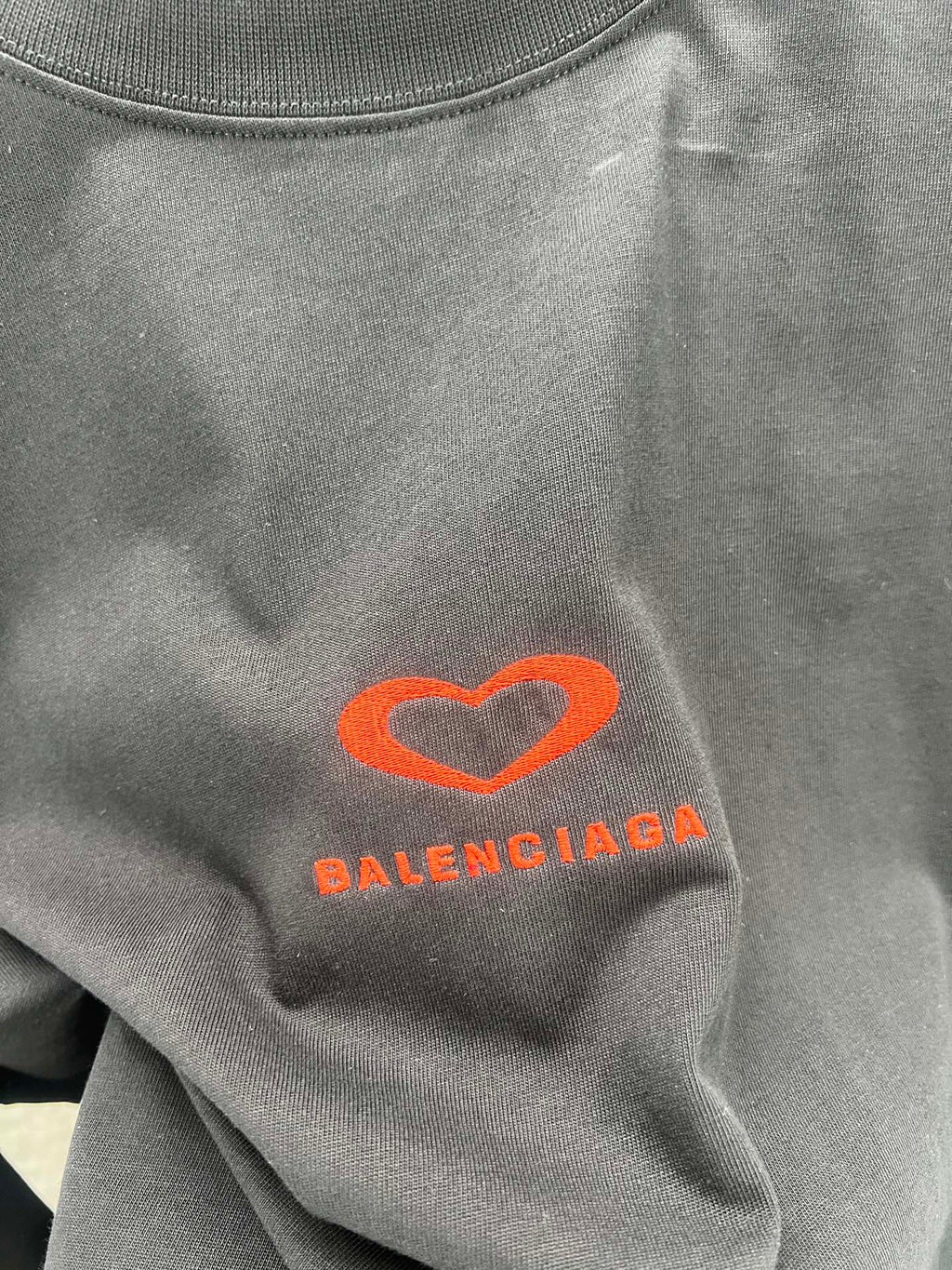 Gray T-shirt close-up of heart logo and Balenciaga text in orange-red
