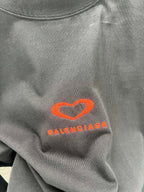 Gray T-shirt close-up of heart logo and Balenciaga text in orange-red