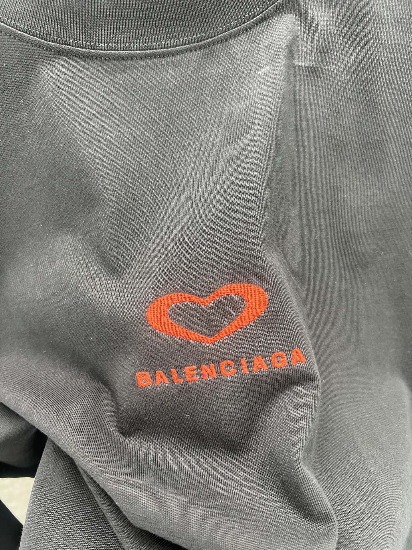 Gray T-shirt close-up of heart logo and Balenciaga text in orange-red