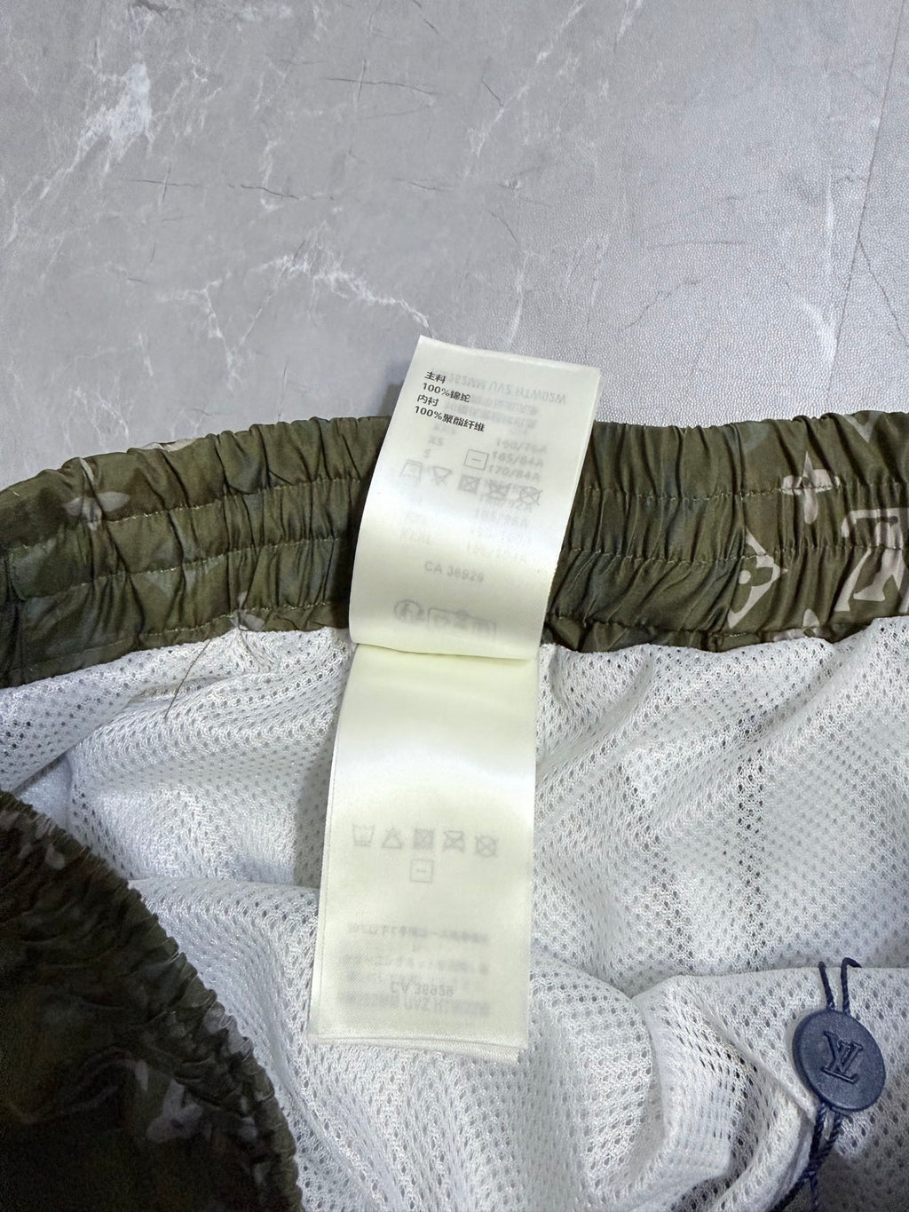Louis Vuitton shorts care tag on white mesh with olive elastic waistband