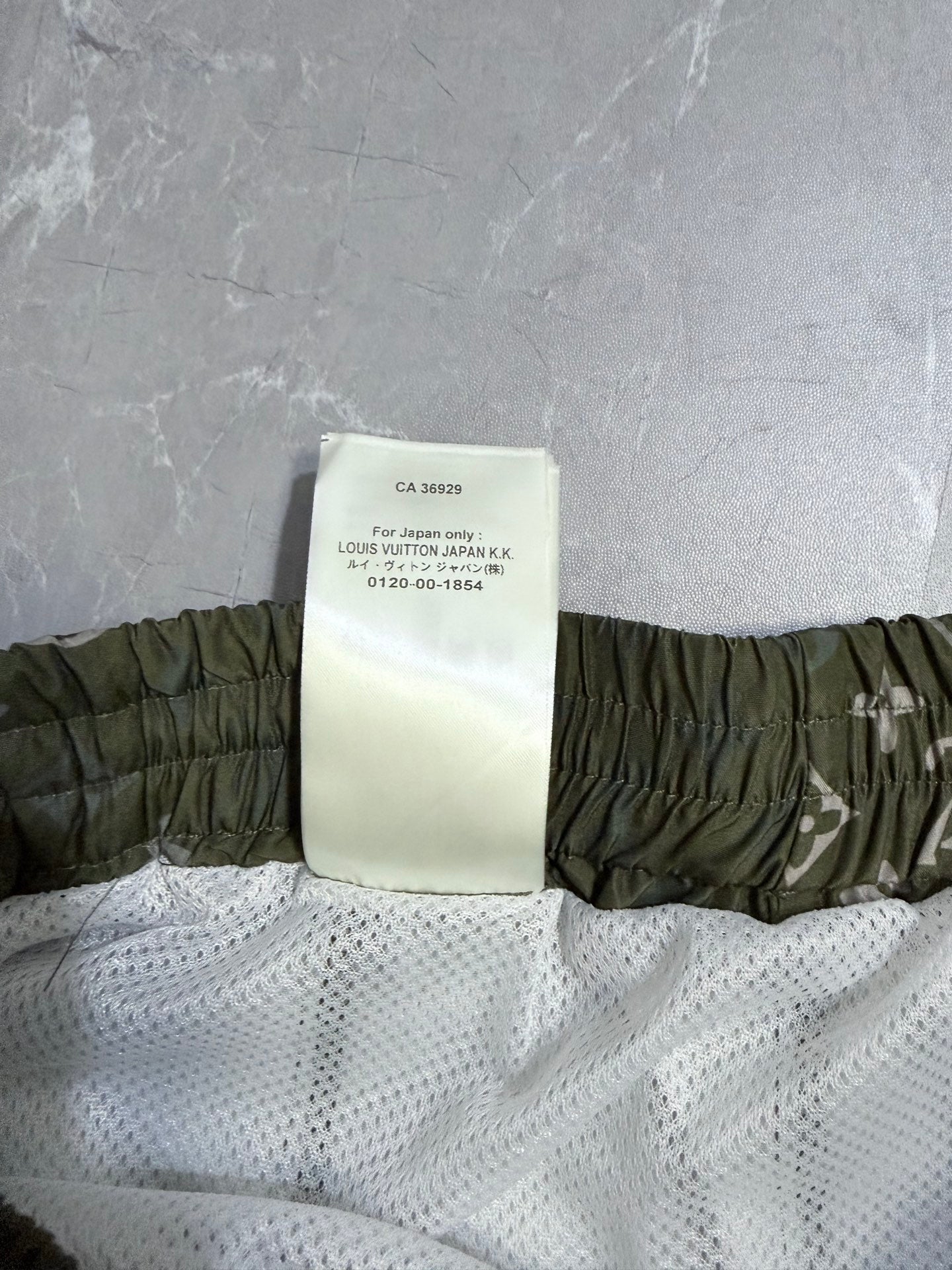 Louis Vuitton shorts product tag on white mesh lining with olive elastic waistband