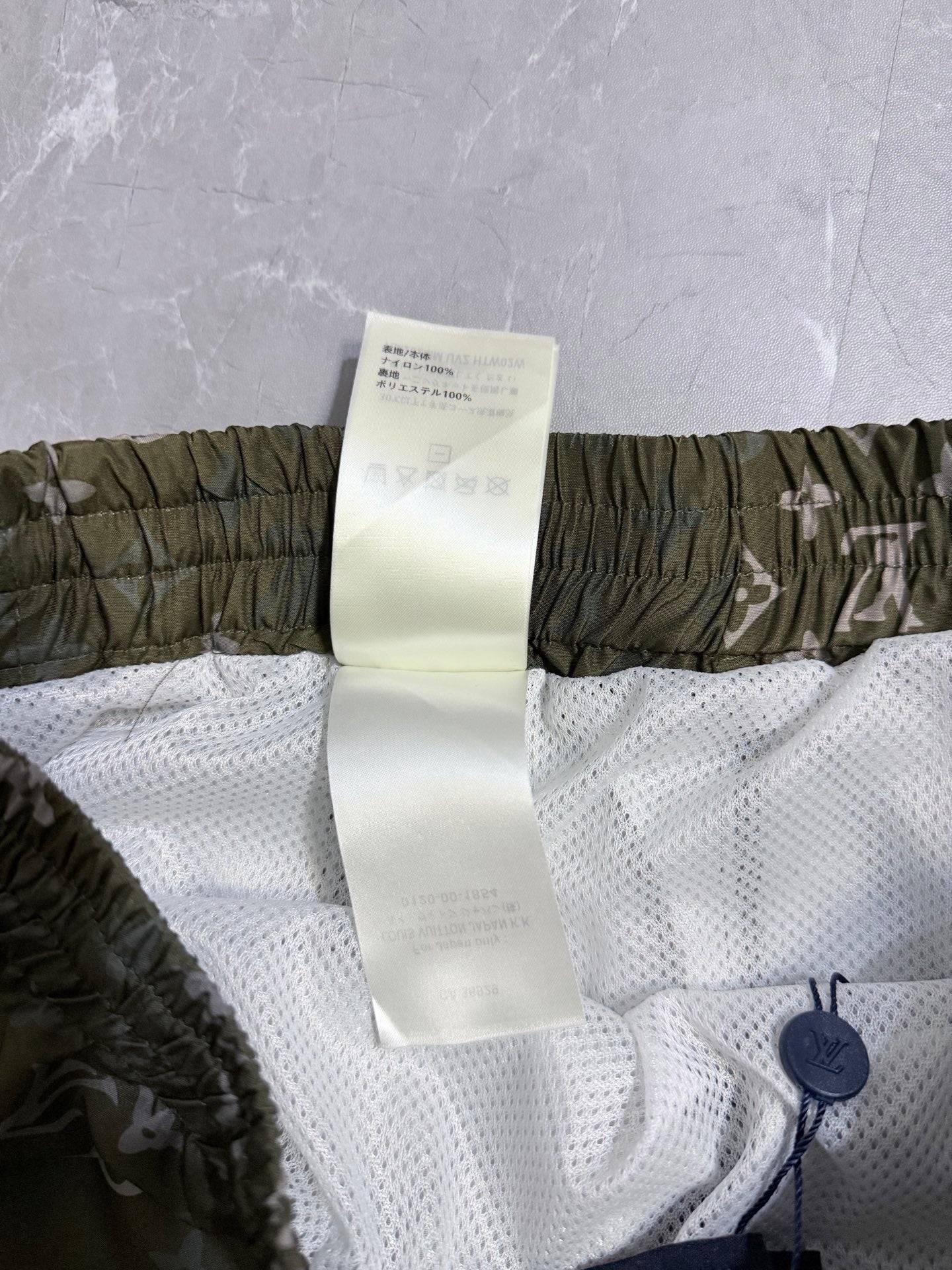 Louis Vuitton shorts care label on white mesh with olive elastic waistband