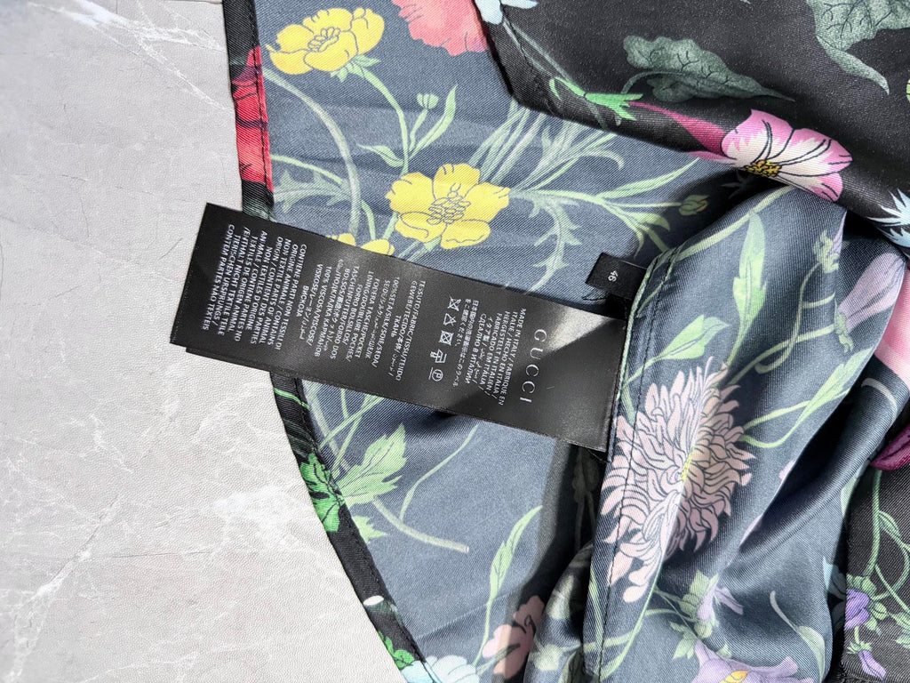 Floral long-sleeve shirt fabric close-up with black size/label tags