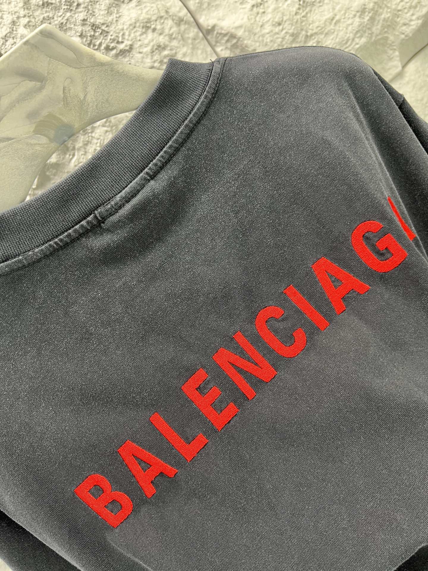 Black short-sleeve shirt close-up with red Balenciaga text print