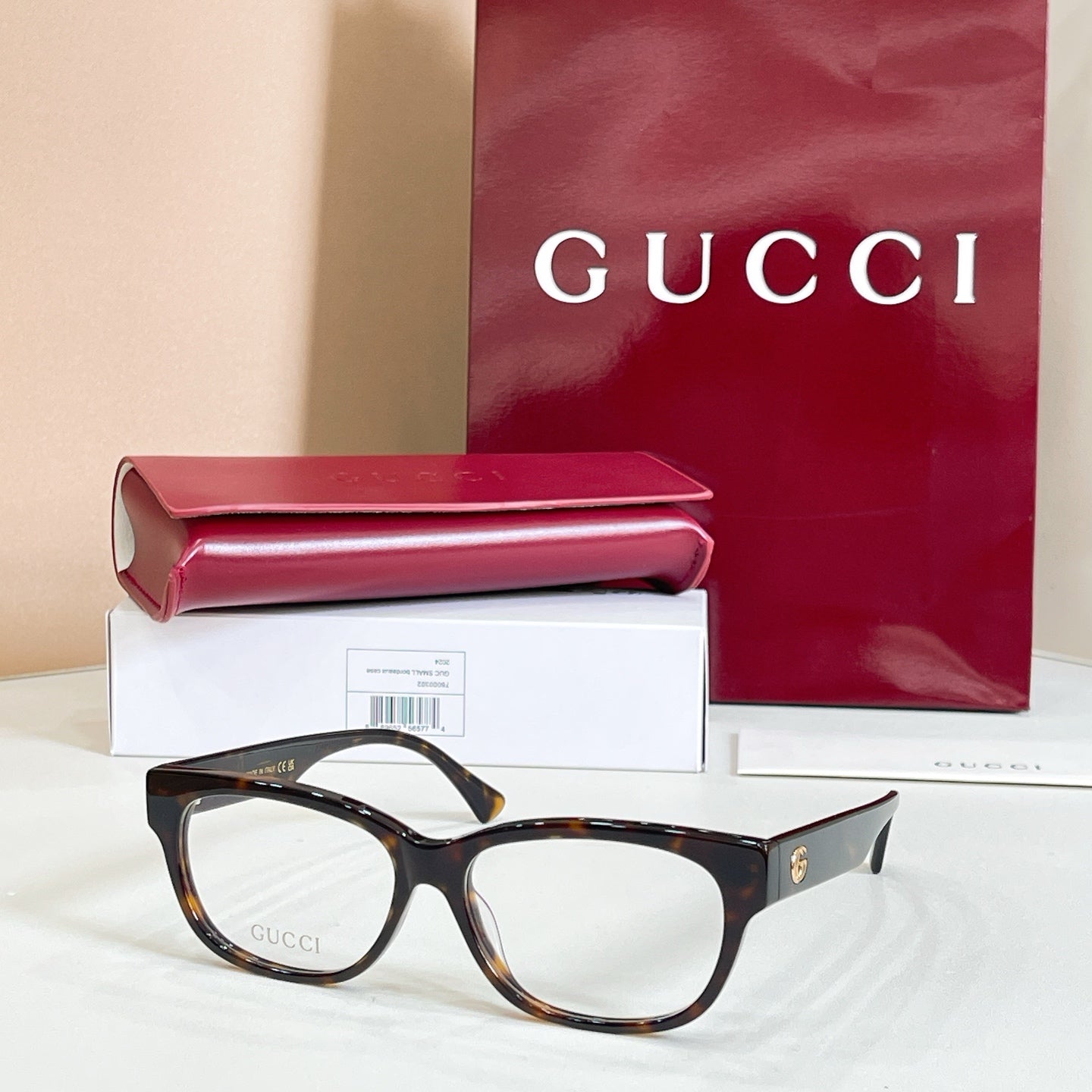 Black tortoiseshell glasses with red and green striped temple details, with case and box.