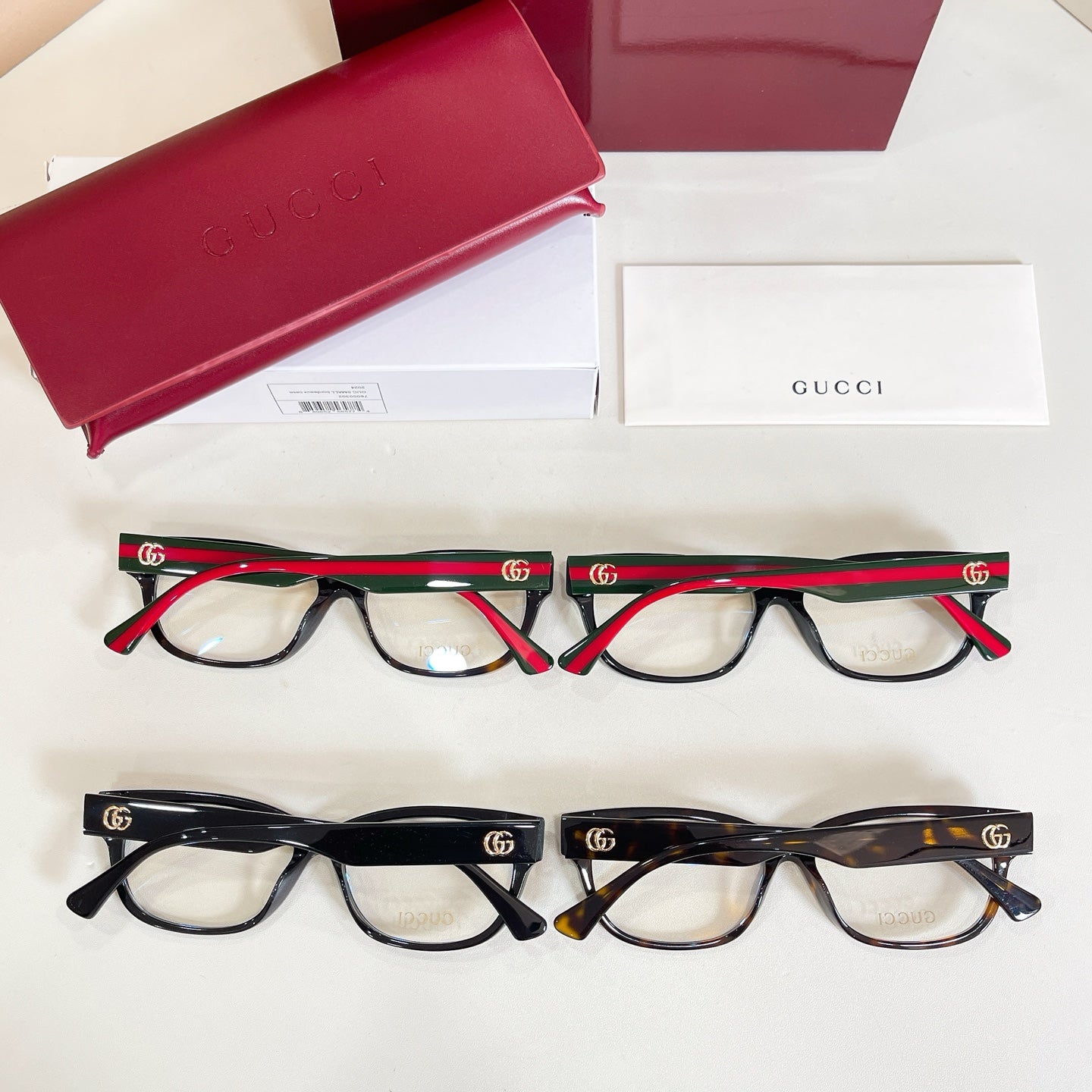 Two pairs of glasses with red and green stripe temples, shown with red case and boxes.