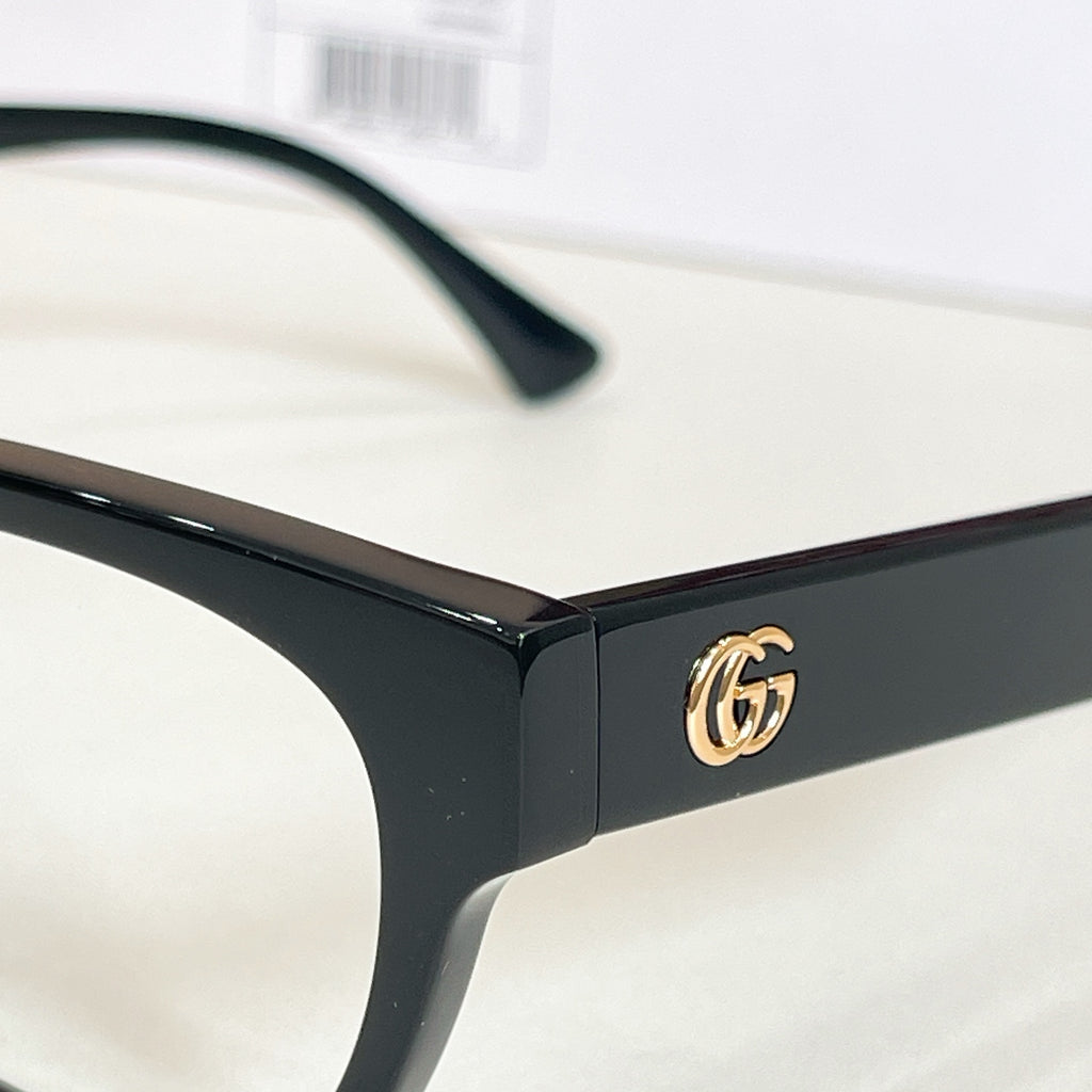 Black glasses close-up with gold double-G logo on the temple and curved temple end.