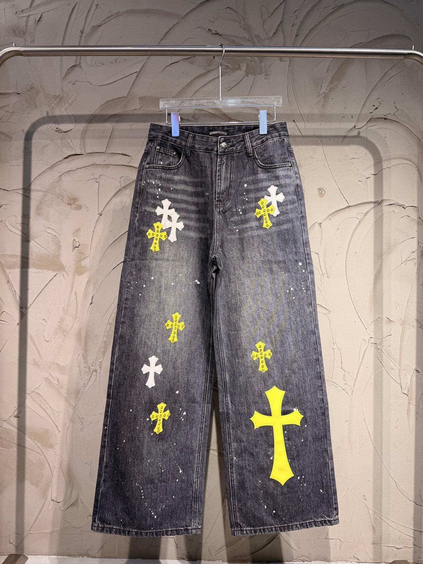 Dark gray denim pants with yellow and white cross patches on legs