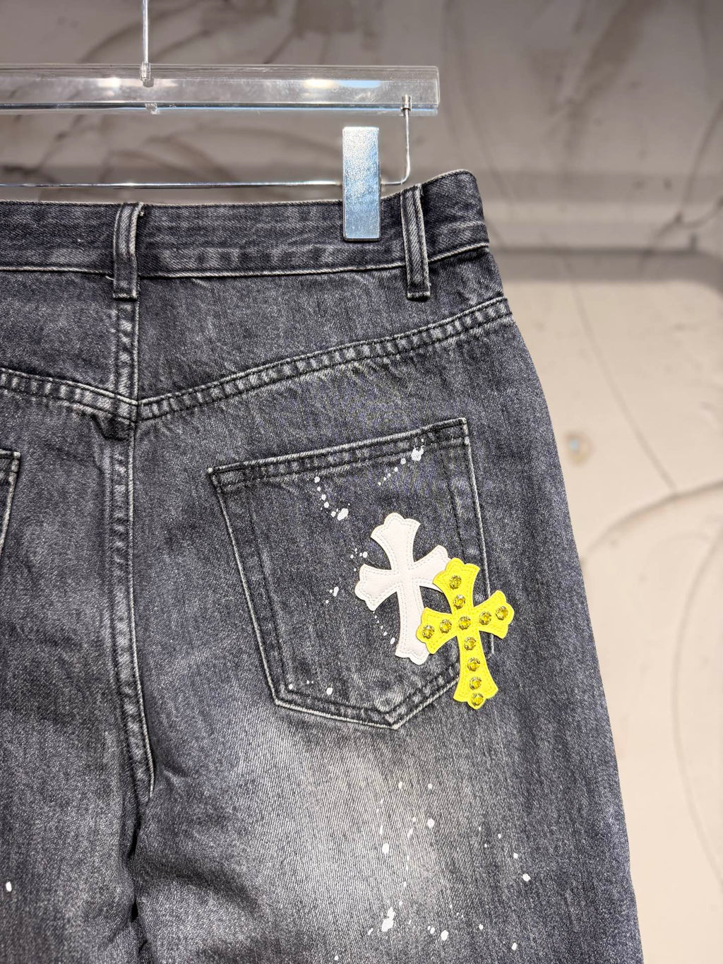 Dark gray denim pants with back pocket and yellow plus white cross graphic