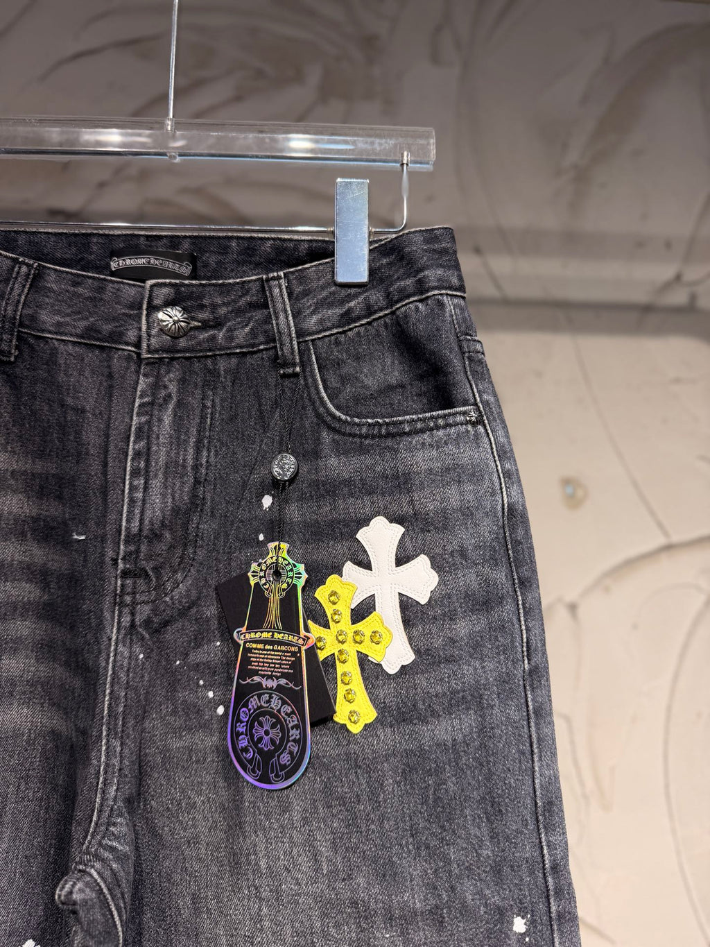 Dark gray denim pants with front pocket area and cross graphic patch
