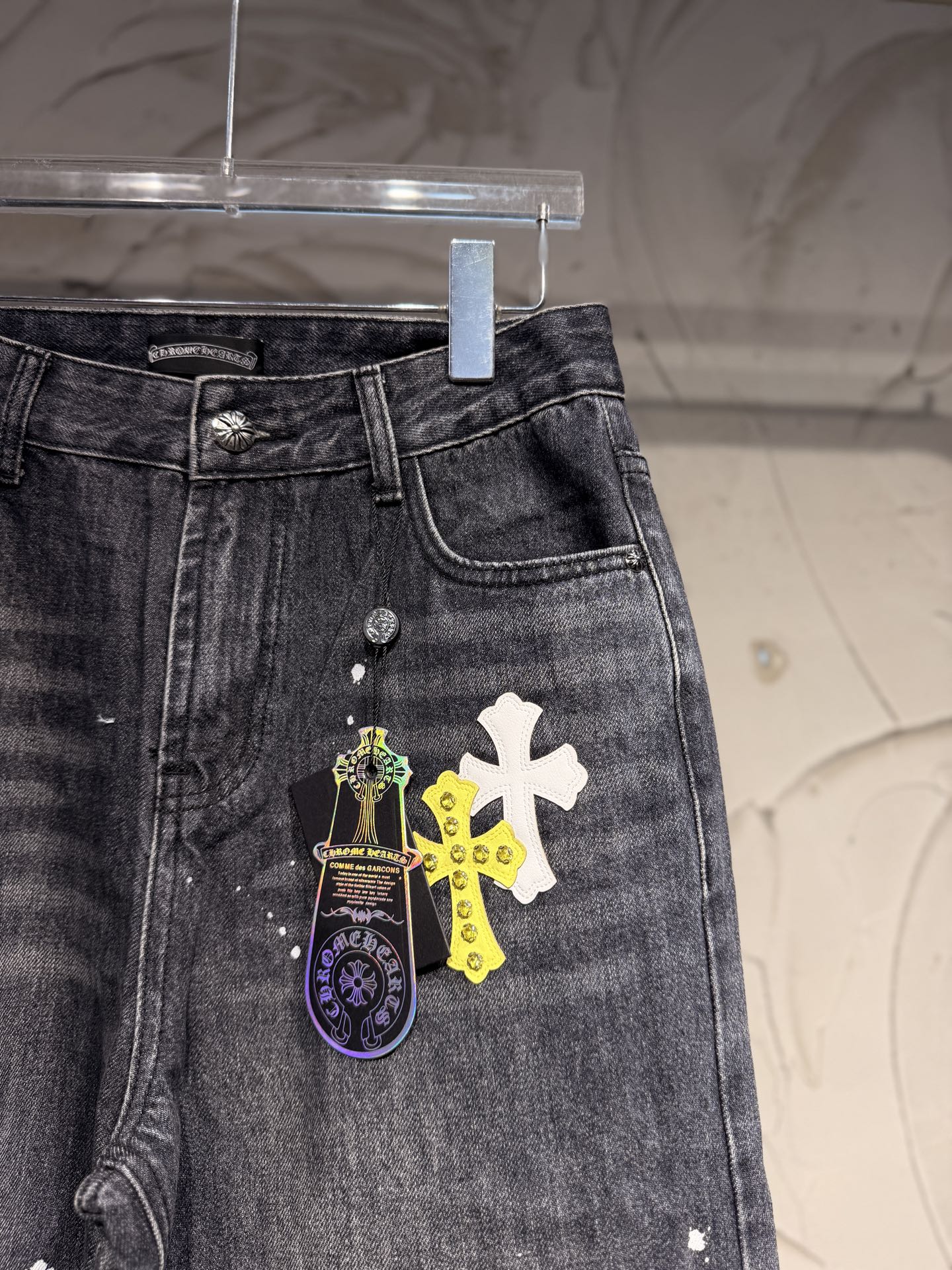 Dark gray denim pants with front pocket area and cross graphic patch