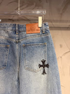 Light blue denim pants with leather-logo label and black cross patch on the pocket