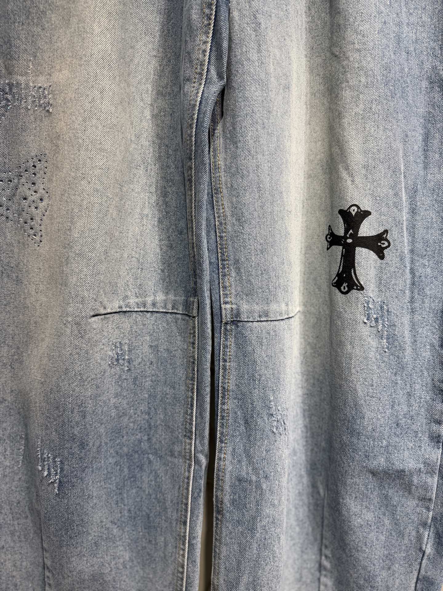 Light blue denim pants with black cross graphic on the side seam