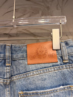 Blue denim pants waistband with brown leather logo patch and metal button