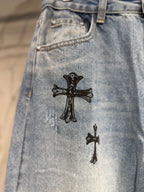 Light blue denim pants with two black cross patches on the front
