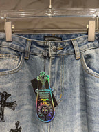 Light blue denim pants with belt loops and a colorful cross graphic on the front