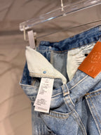 Light blue denim pants with adjustable waistband tag and cross graphic on the leg