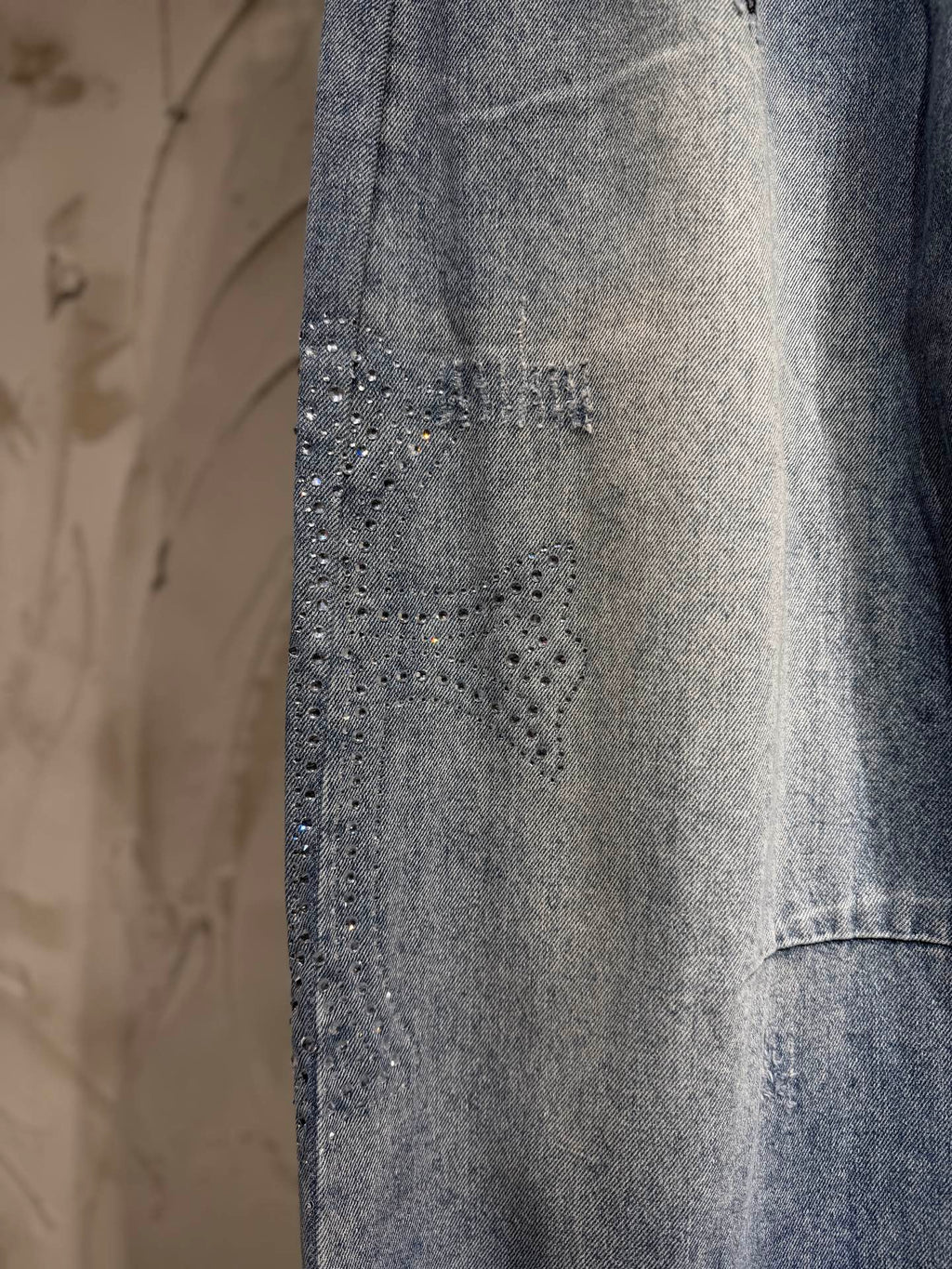 Light blue denim pants with textured studded detailing on the front leg