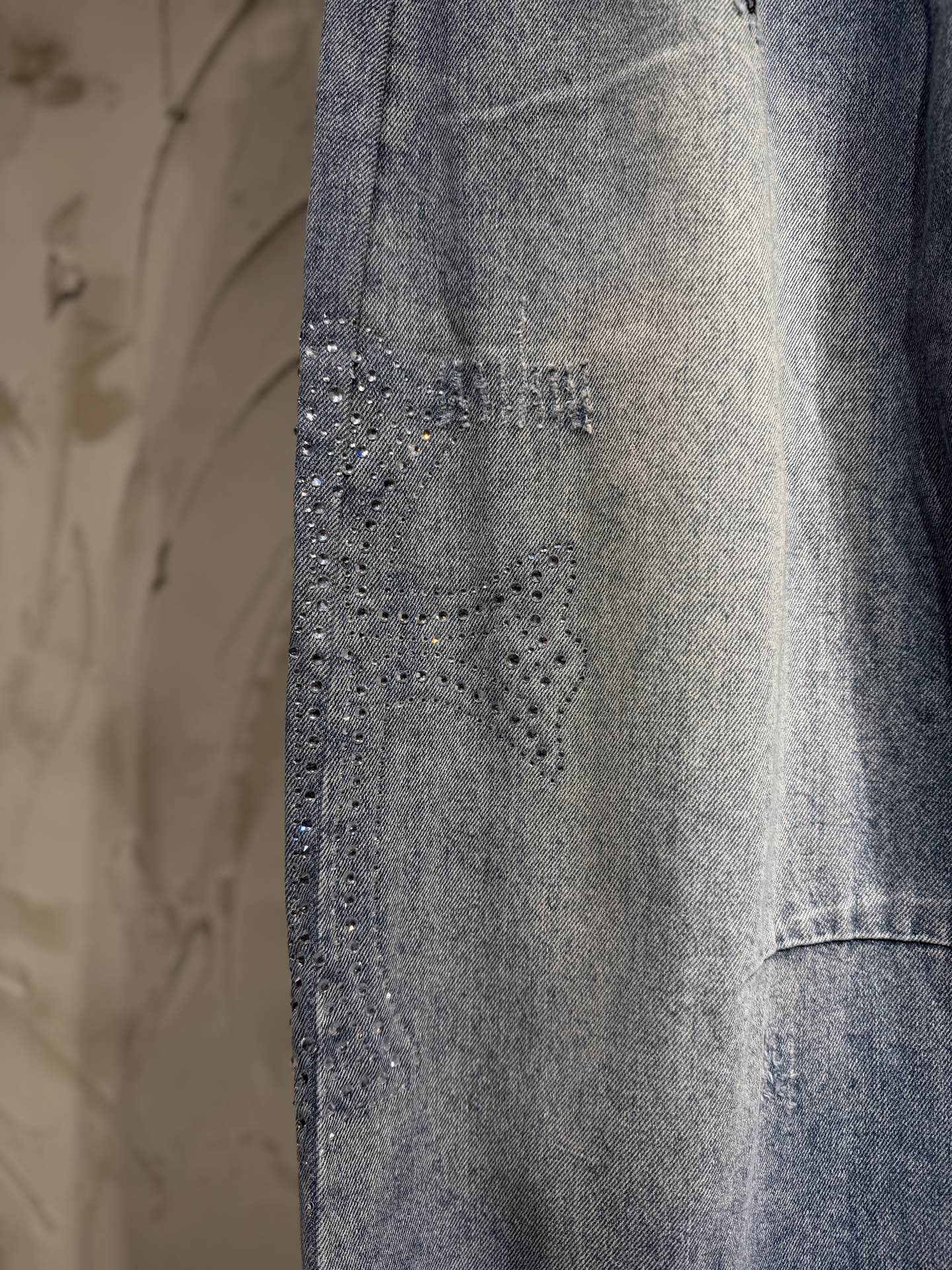 Light blue denim pants with textured studded detailing on the front leg