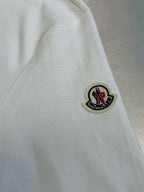 Close-up of white polo sleeve with round logo patch and black outline