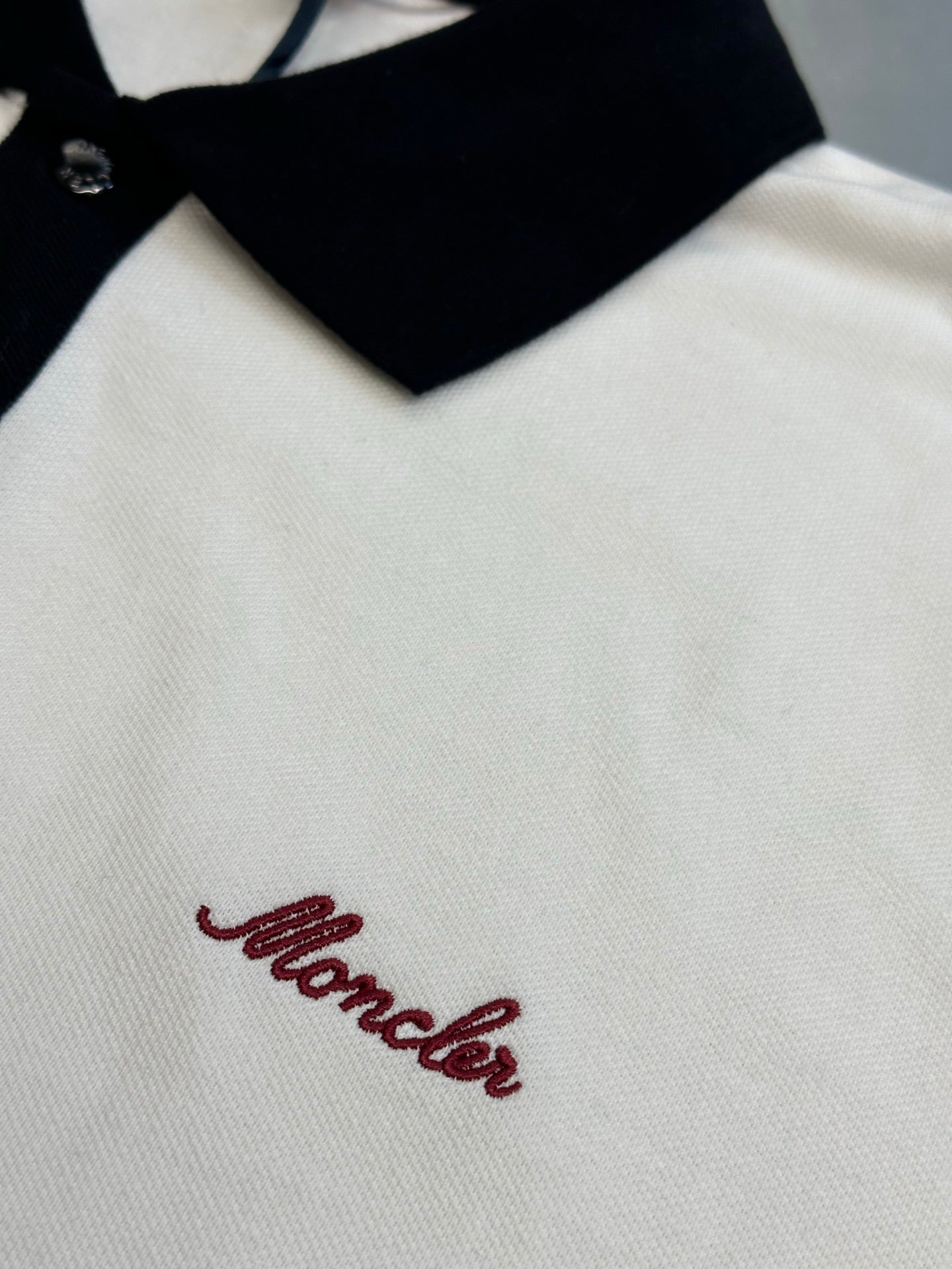 Close-up of polo chest with red script logo on white fabric