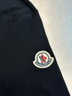 Moncler sleeve patch on navy polo shirt near the shoulder seam