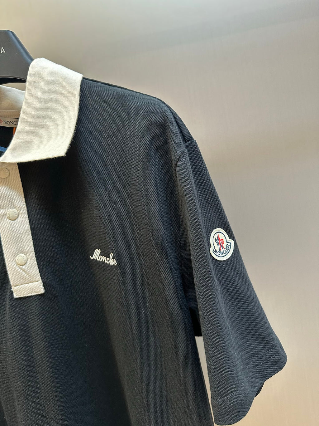 Moncler navy polo shirt side view with cream collar and circular sleeve logo patch