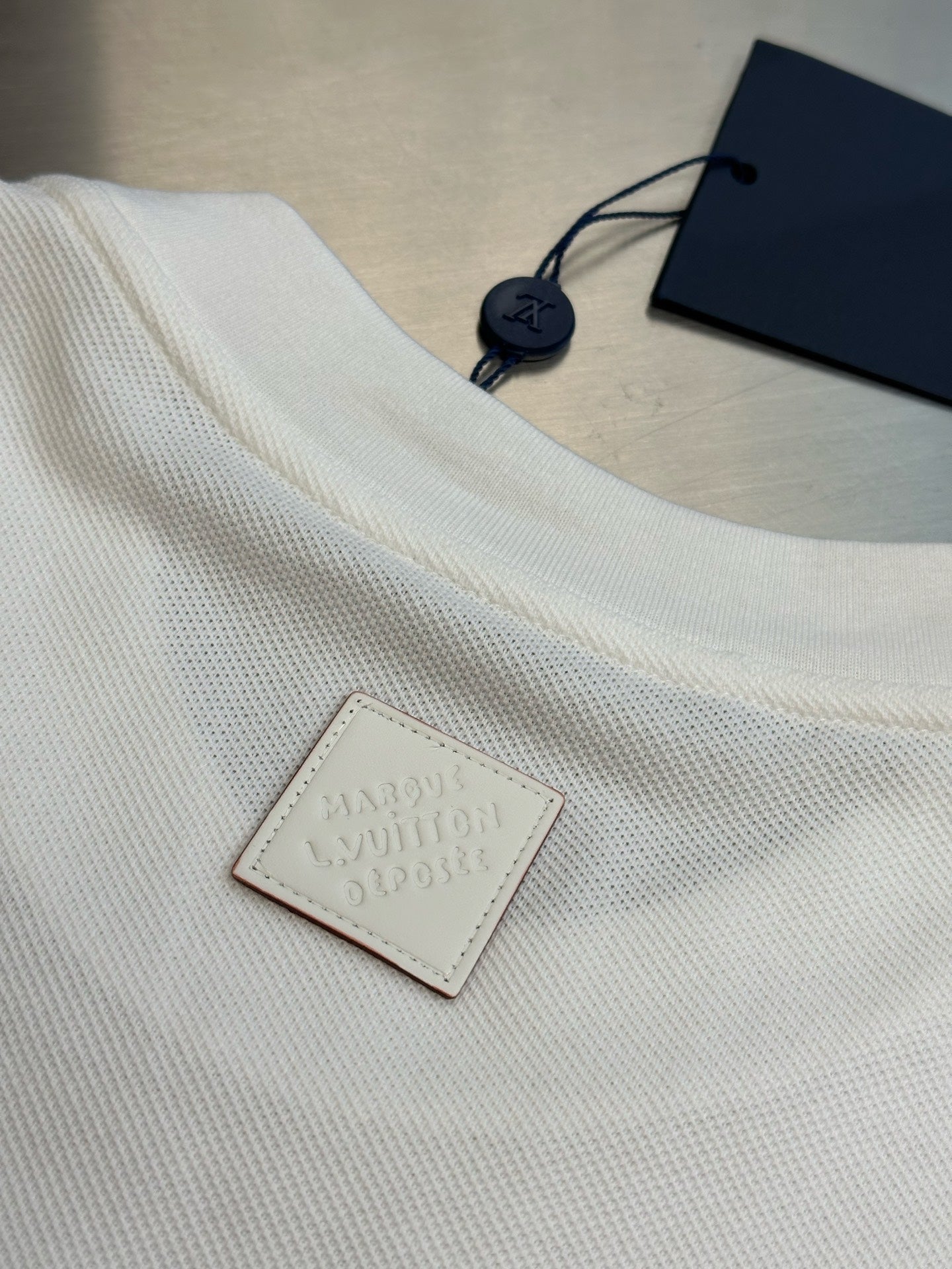 White T-shirt with embossed leather brand patch and navy hang tag