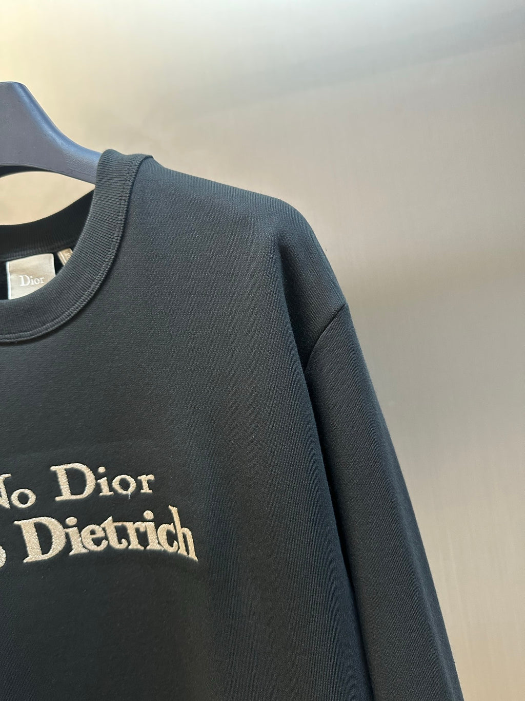 Black sweatshirt sleeve with 'No Dior No Dietrich' text print