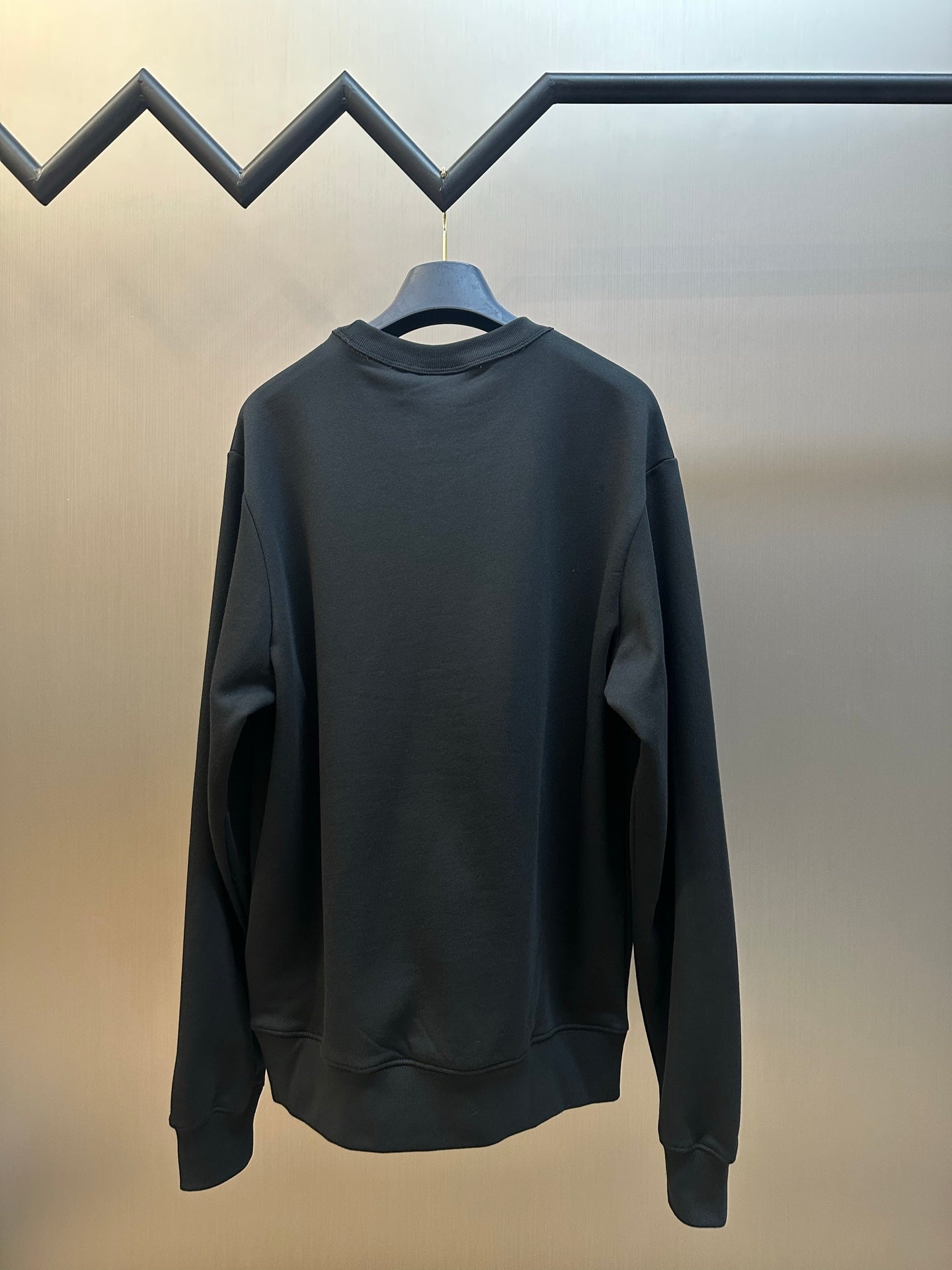 Black crewneck sweatshirt back view, long sleeves and ribbed hem