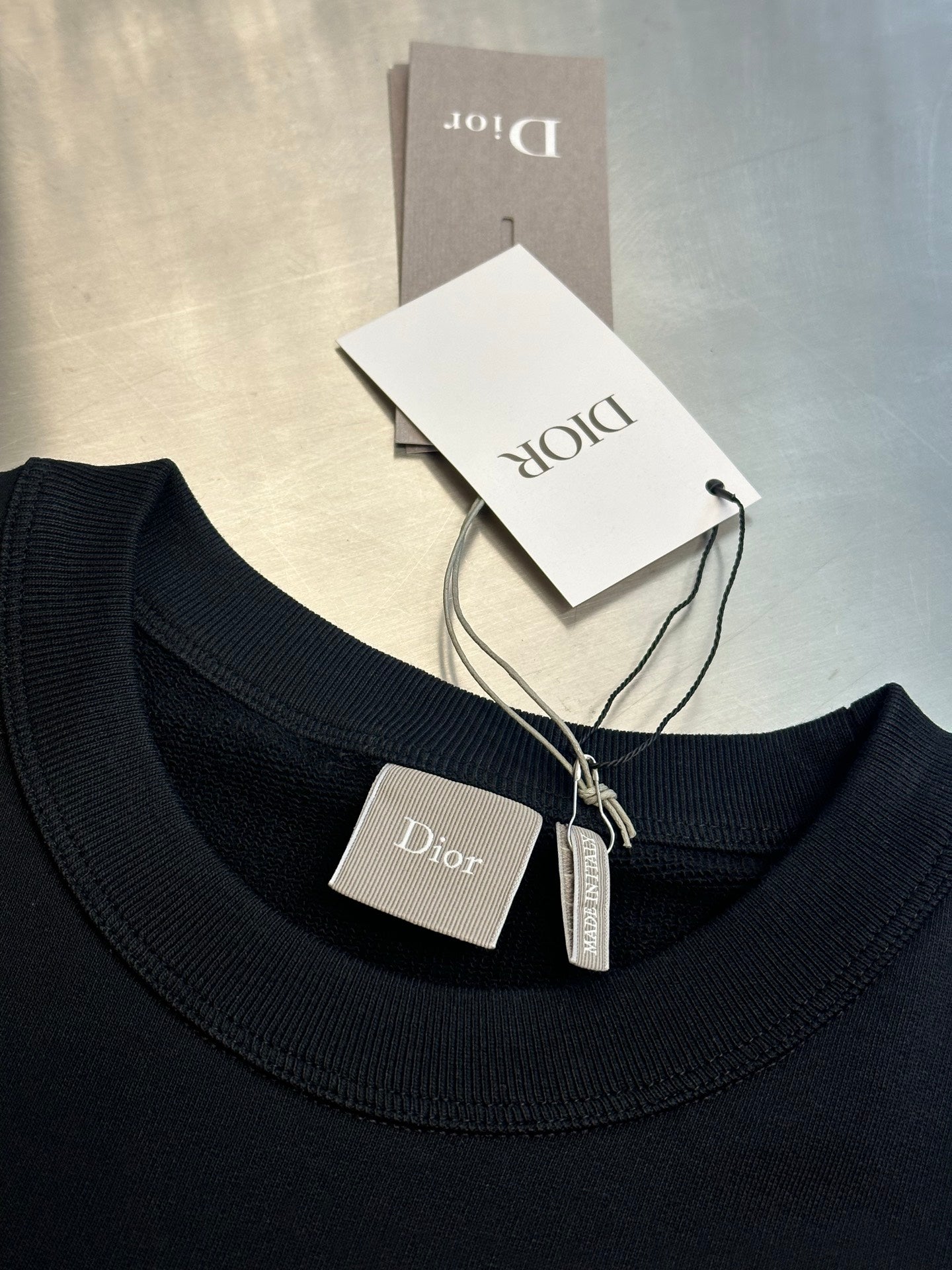 Black crewneck sweatshirt collar with Dior label and hanging size tag
