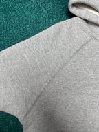 Light gray hoodie close-up with stitched hood seam and sleeve panel