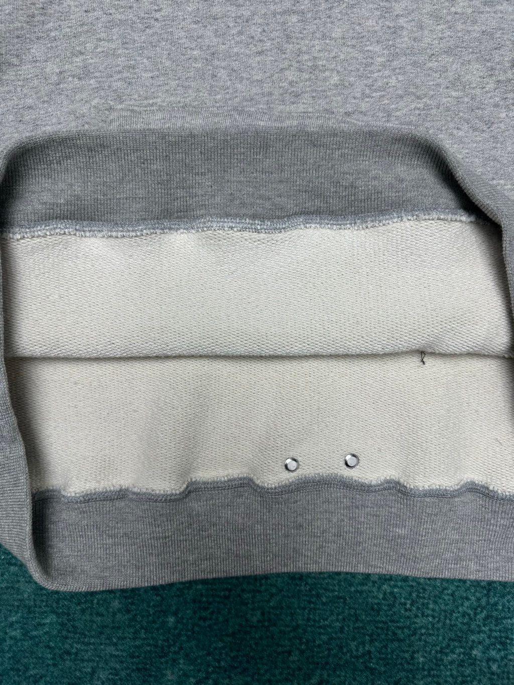 Light gray hoodie hem with ribbed trim and two metal eyelets