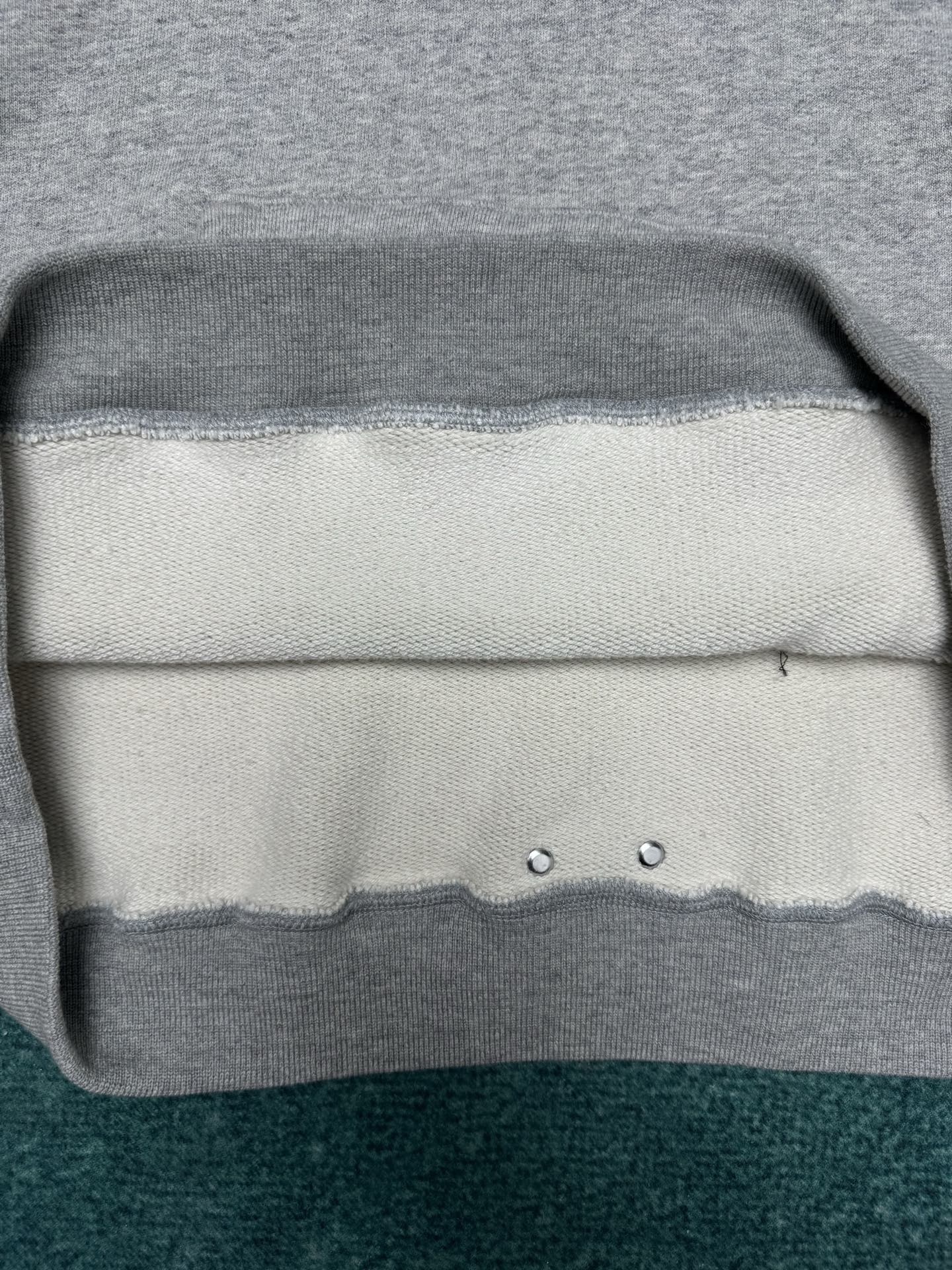 Light gray hoodie hem with ribbed trim and two metal eyelets