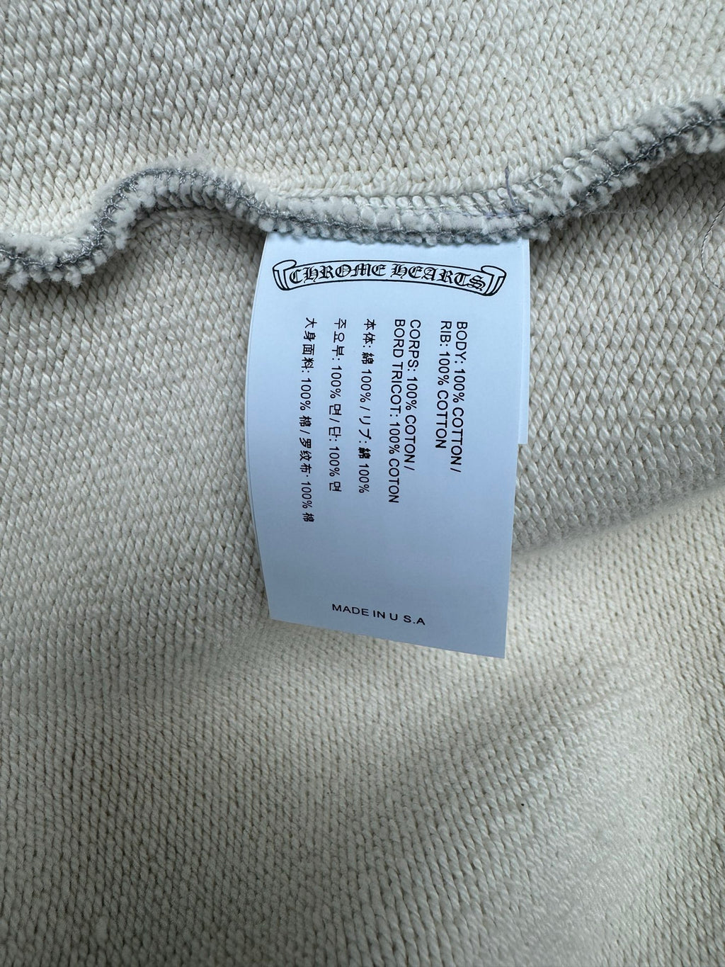 Light gray hoodie with woven brand and size label near the hem