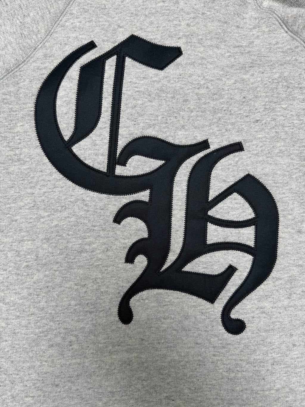Light gray hoodie with black decorative monogram logo on chest